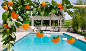 Puffy felt orange garland used as backdrop for summer celebration