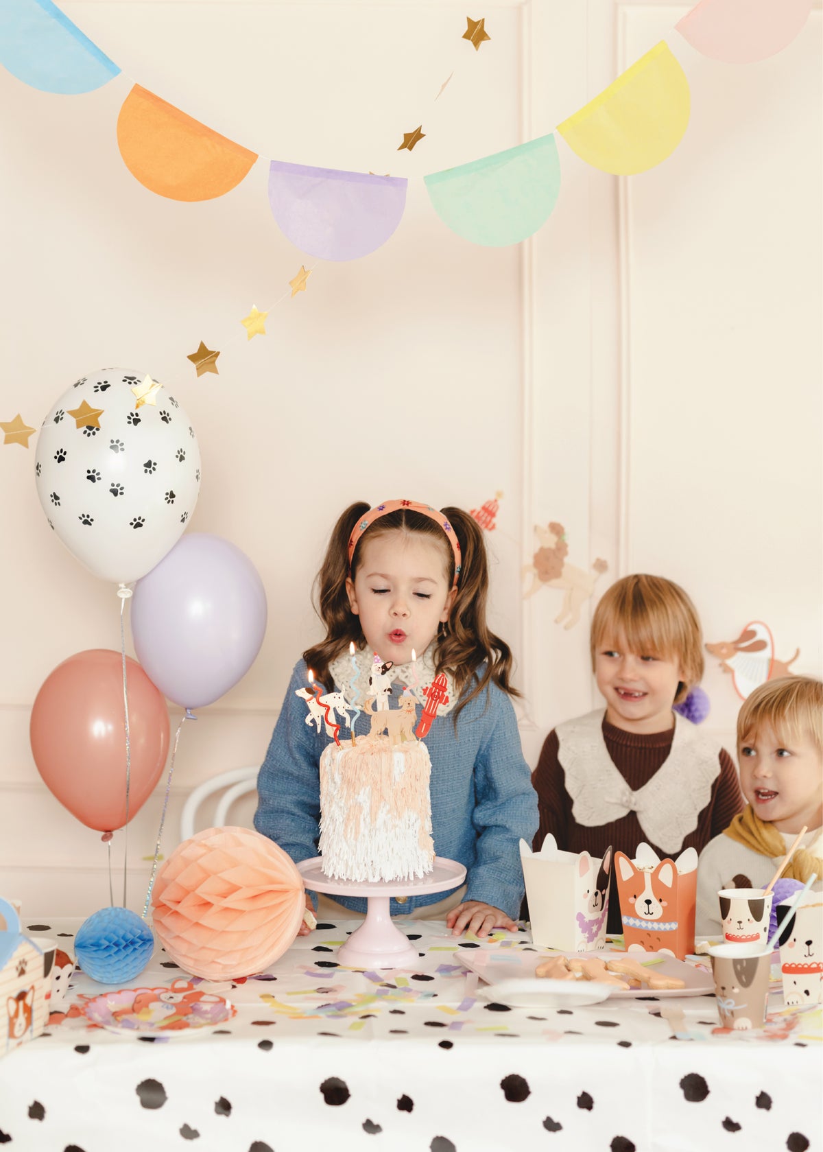 Child blowing out candles with dog cake toppers