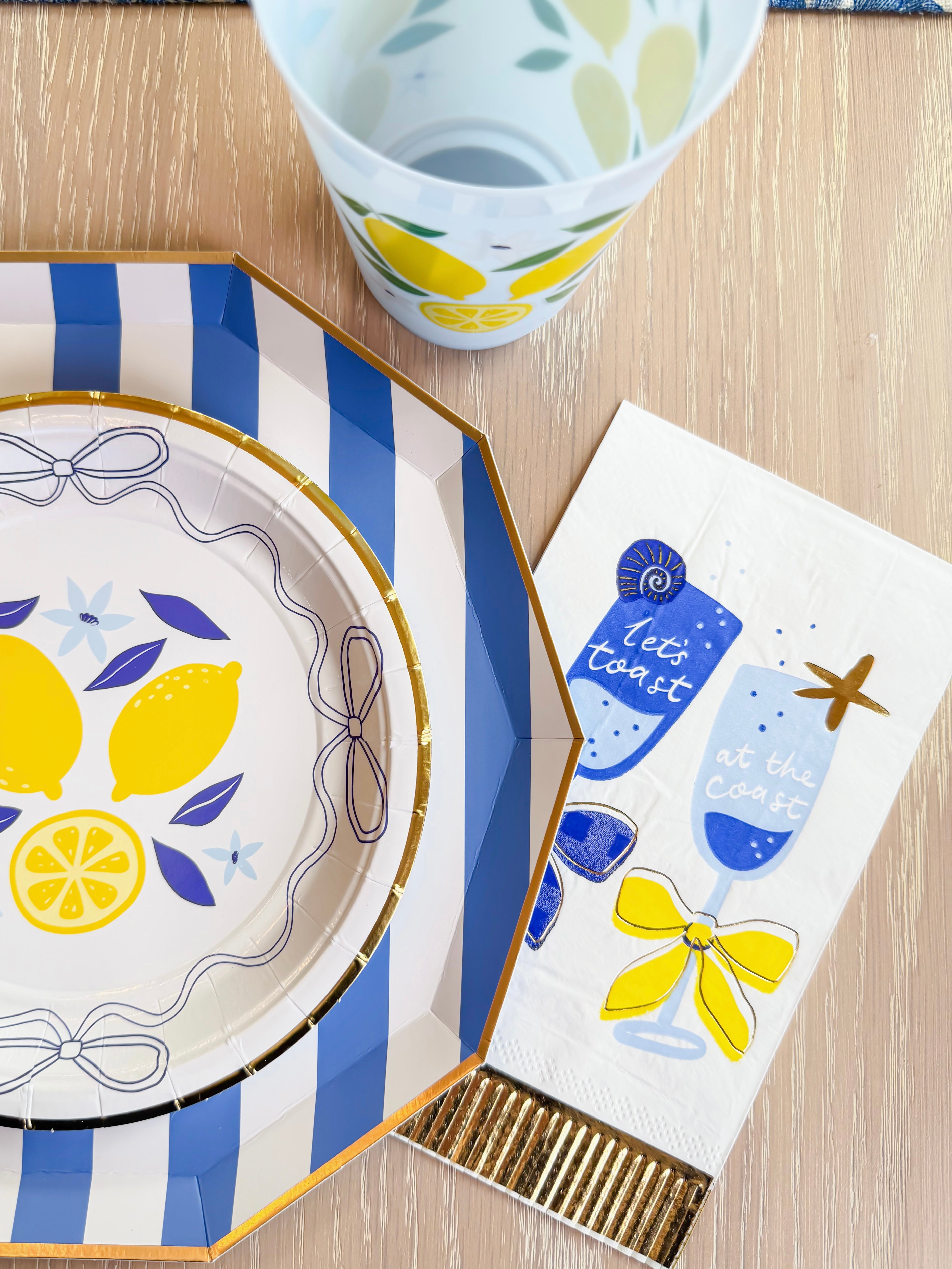 Lemon party plate and cup styled with cocktail-themed napkin reading “Let’s toast at the coast.”