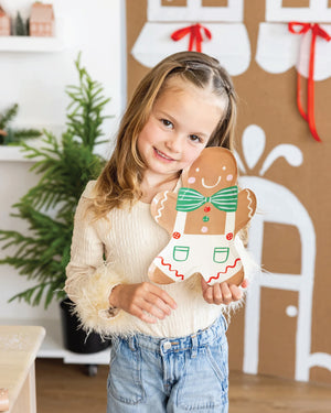 Young girl holding a gingerbread man plate at a gingerbread house decorating party