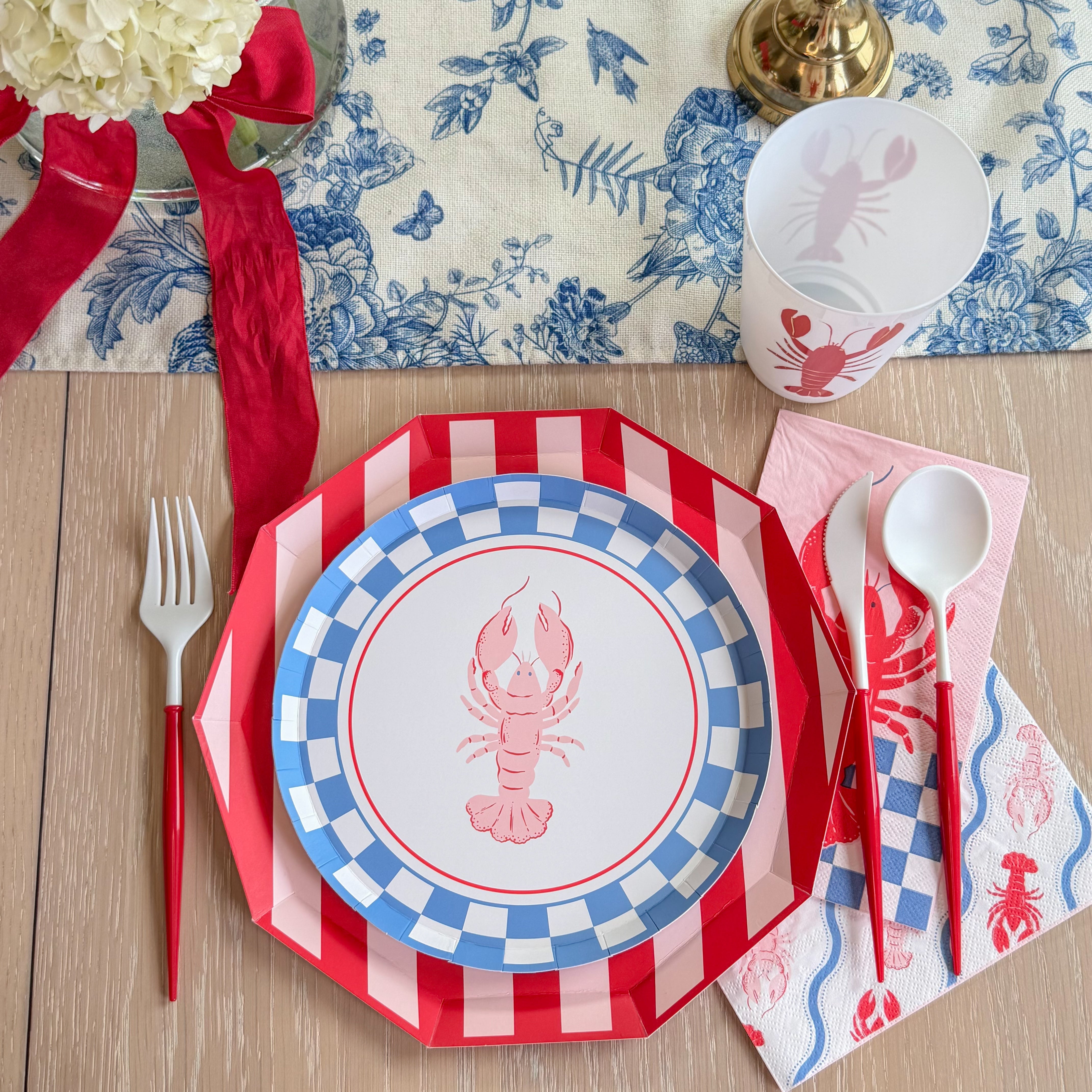 Lobster paper plate with blue check border layered on a red striped octagonal charger.
