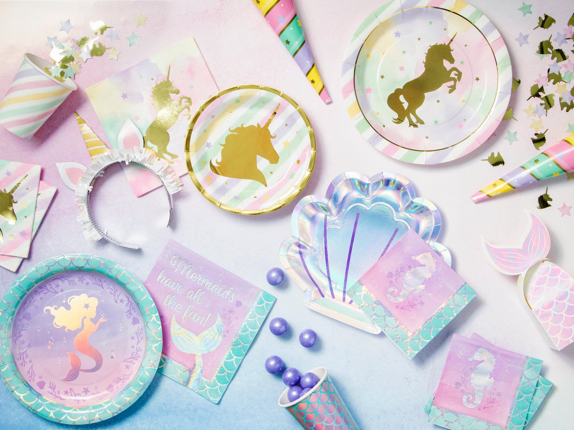 Pastel-colored party supplies with unicorn and mermaid designs on a light blue background.