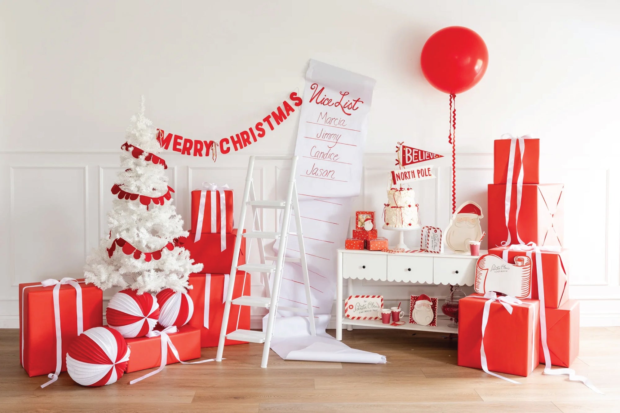 Christmas-themed room with red and white decorations, including a tree, presents, and balloons.