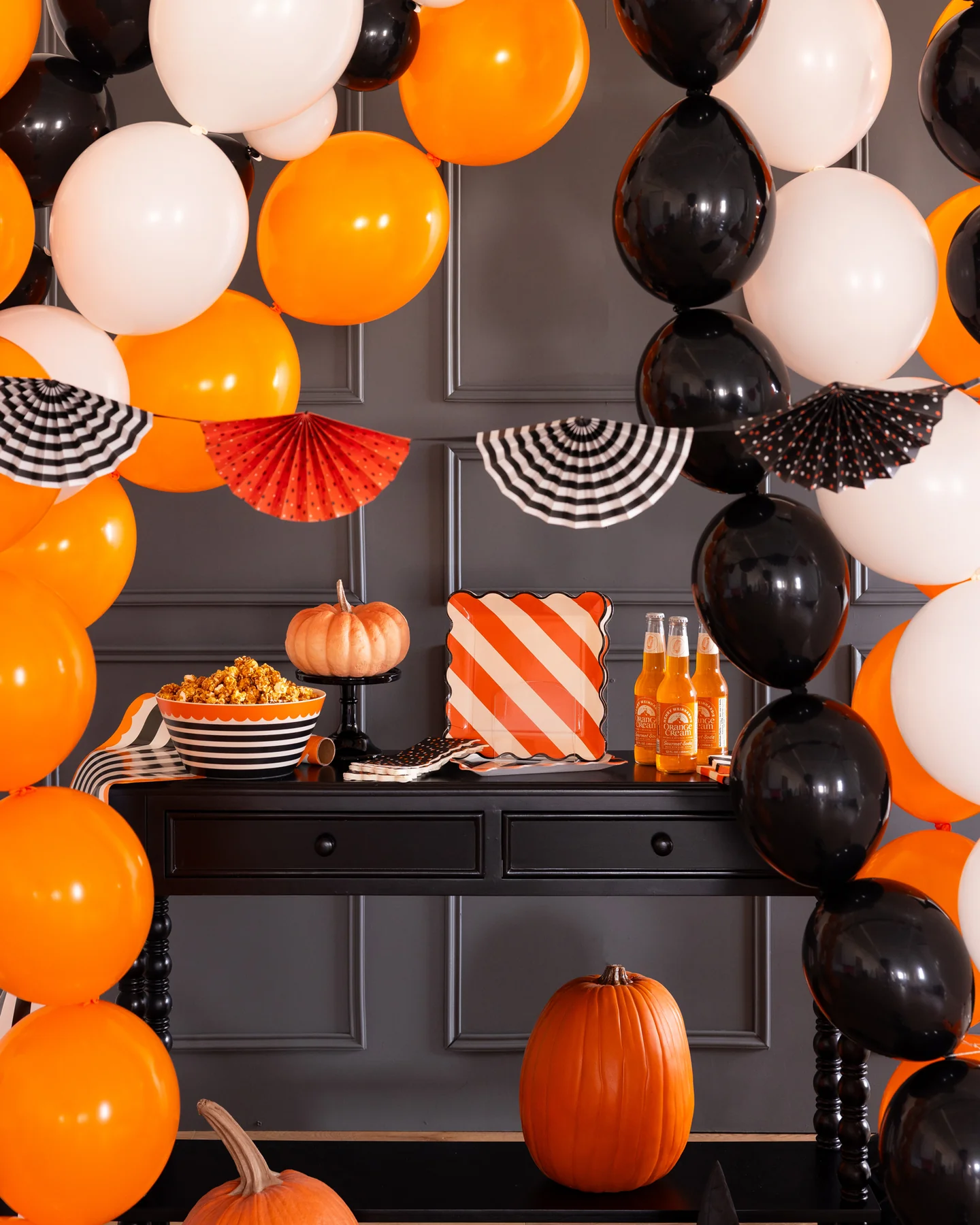 Decorative setup with Halloween party supplies, including an orange and black tissue paper fan bunting