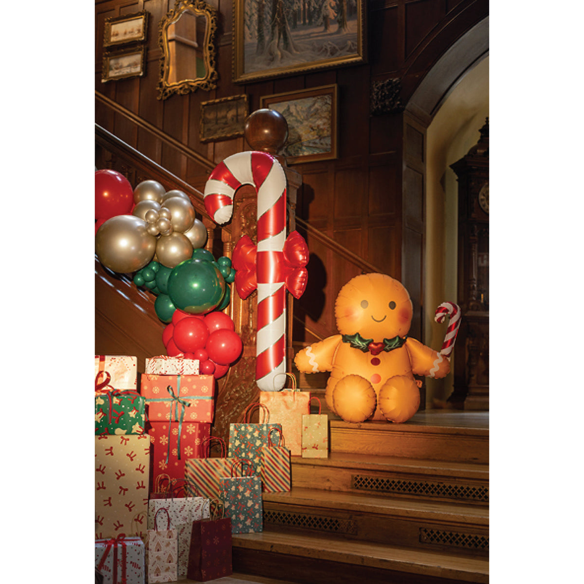 Large candy cane-shaped foil balloon with bright red stripes, white sections, and thin gold accents.