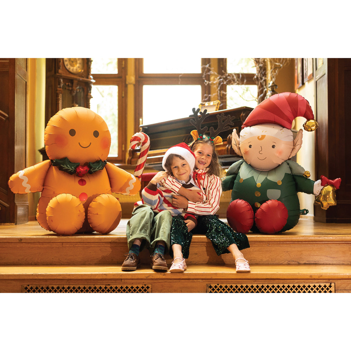 Brown gingerbread man foil balloon with rosy cheeks, red buttons, white icing details, and a green holly collar.

