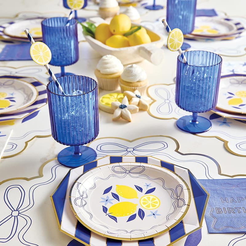 Decorative table setting with blue glasses, lemon-themed plates, and Happy Birthday napkins.