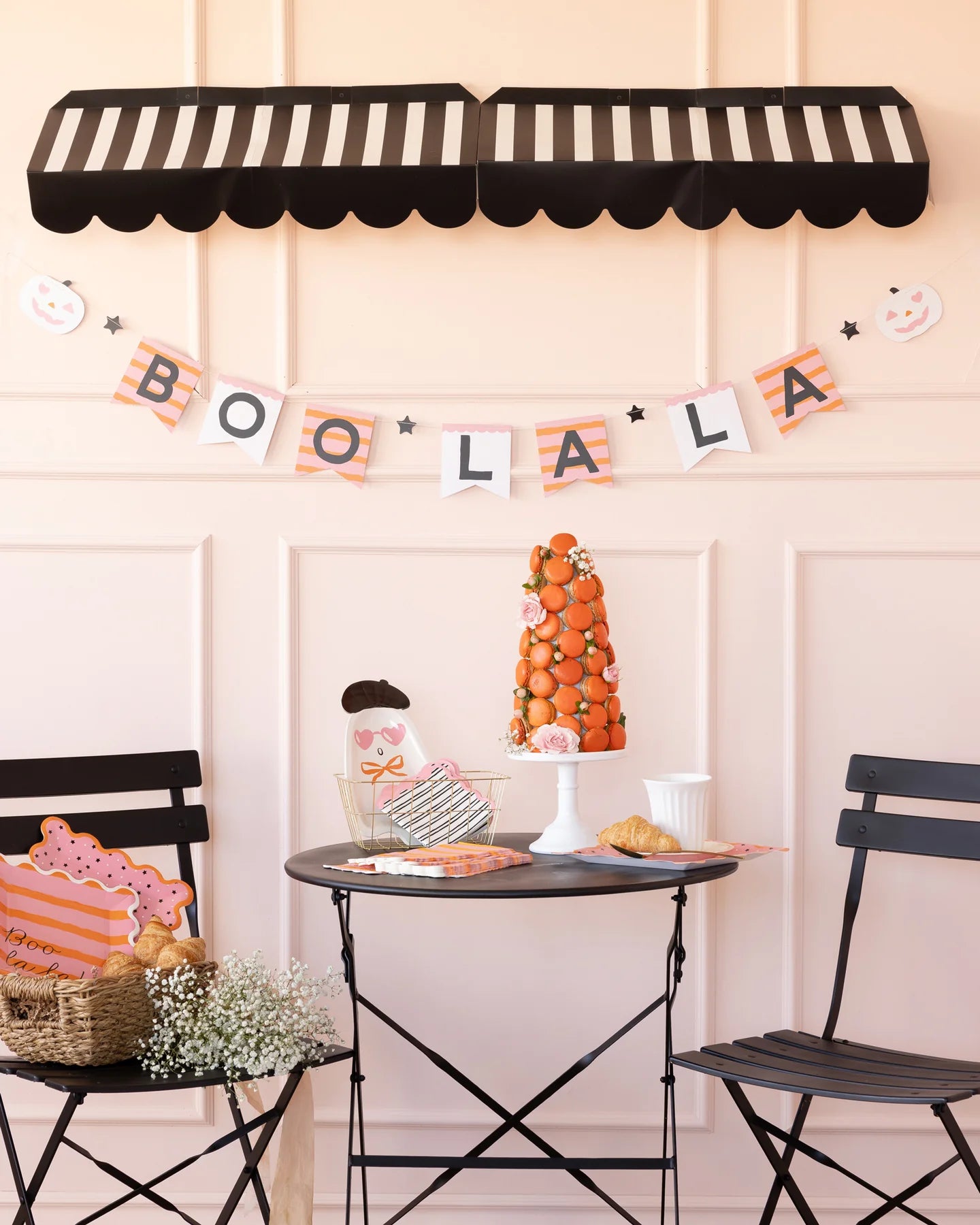 Halloween-themed party with 'BOO LA LA' banner, candy corn display, and black chairs.