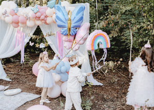 Children hitting a pull string rainbow piñata