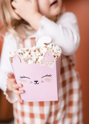 Child holding a pink cat snack box with popcorn