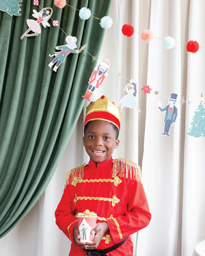 Child holding nutcracker cups with a nutcracker banner set hanging above the child.