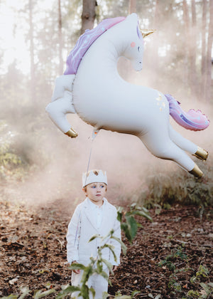 Child holding an inflated giant magical unicorn balloon