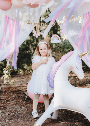 Child posing with a Giant Magical Unicorn Standing Balloon