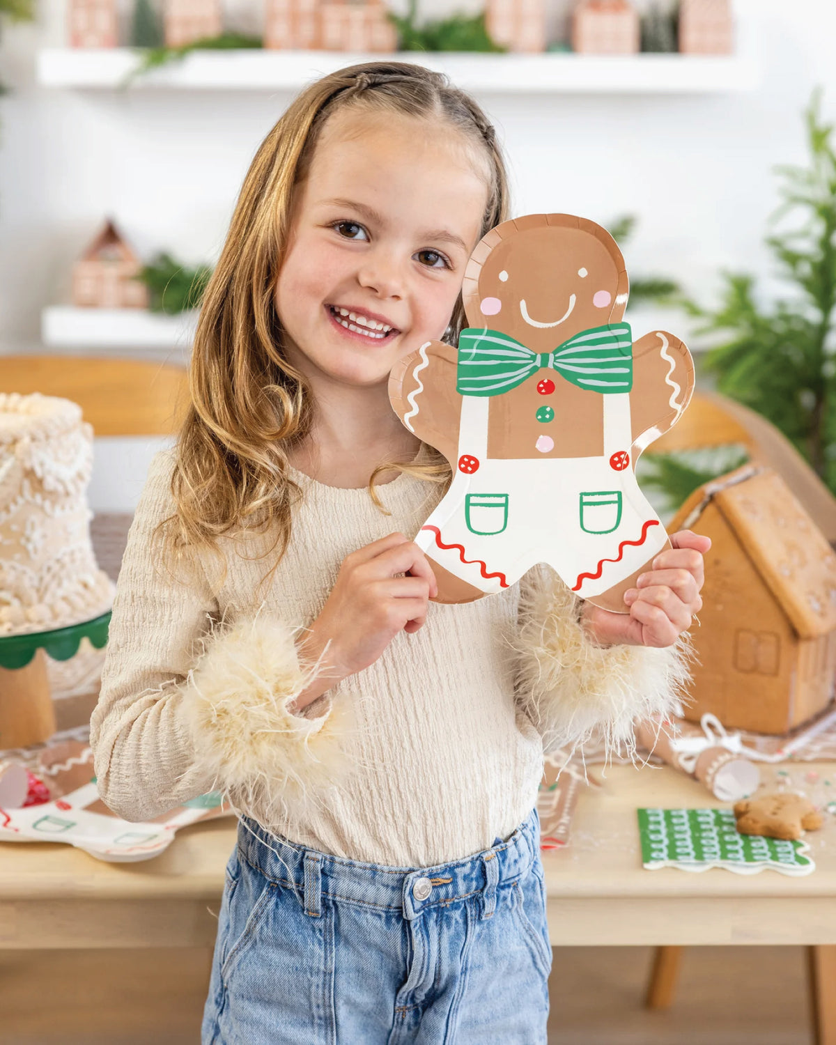 Young girl holding a gingerbread man paper plates at a gingerbread house decorating party