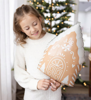 Girl holding a 20in Gingerbread House Balloon with a white string