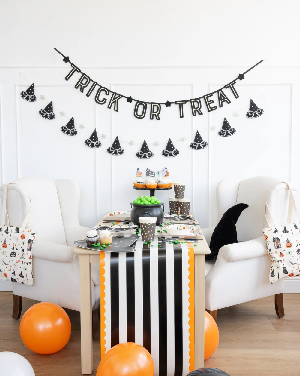 Halloween party table setup with 'Trick or Treat' banner and witch hat garland