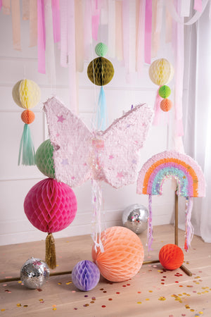 Hanging party decor including a butterfly piñata and rainbow piñata