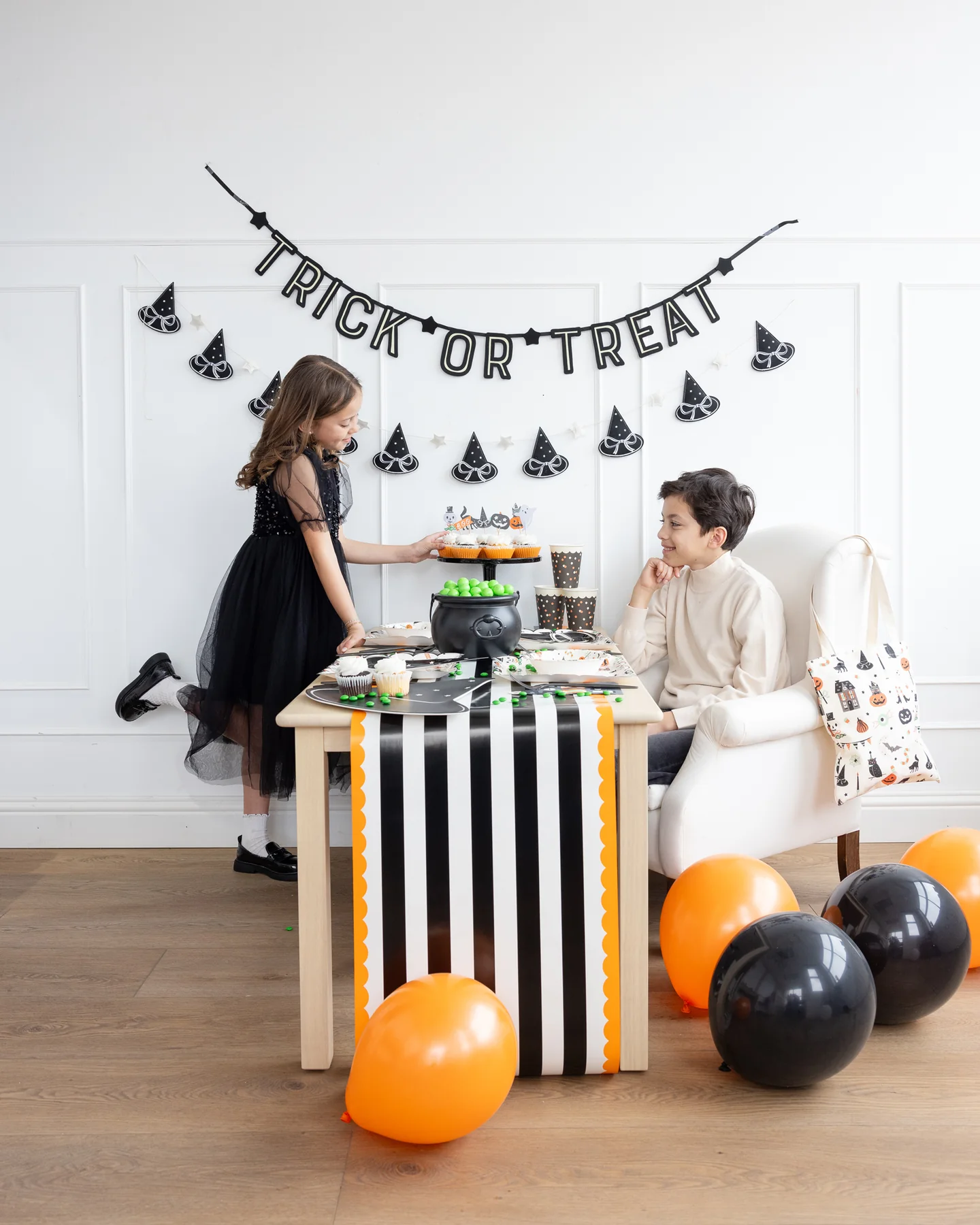 Children at a Halloween party with a 'Trick or Treat' banner and a Orange & Black Striped Paper Table Runner 