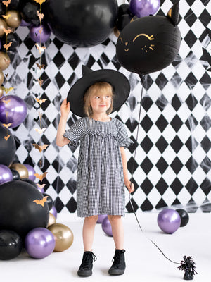 little witch holding black cat balloon
